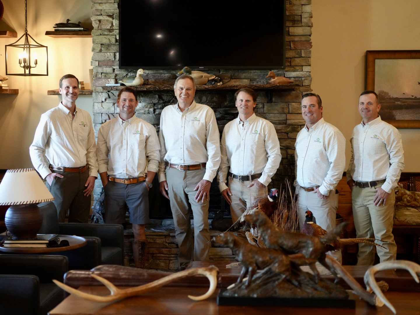 Group of men in a lodge setting with hunting decor, possibly related to the main landing page.